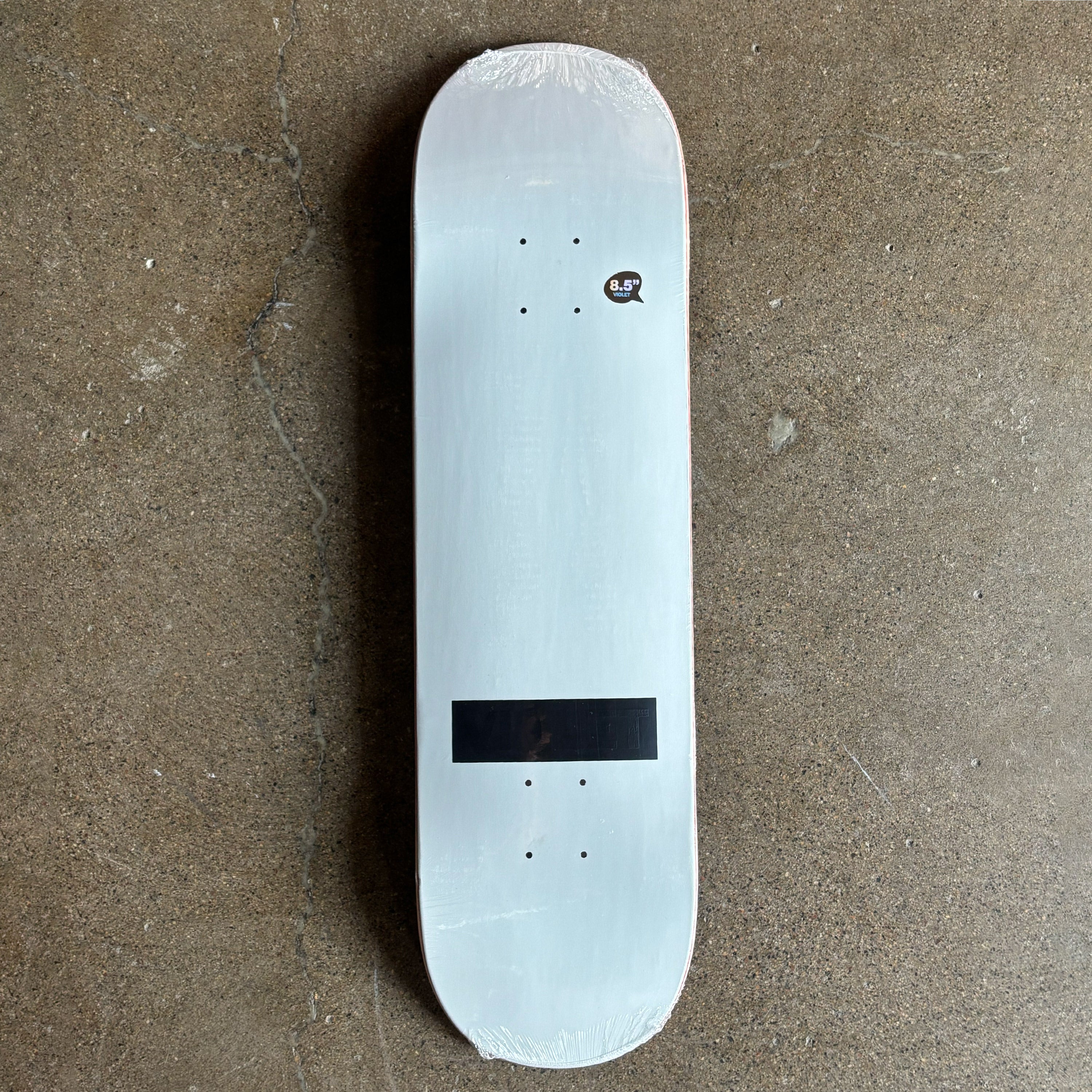 Full image of skateboard deck. White deck with black on black violet logo stamp.